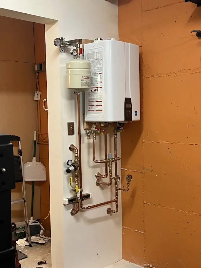 Plumbing technician inspecting water heater connections in Liberty